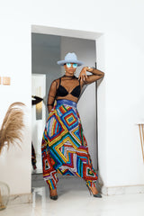 A woman posing in multicolored african print parachute pants.