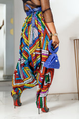 A woman posing in multicolored african print parachute pants.
