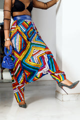 A woman posing in multicolored african print parachute pants.