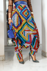 A woman posing in multicolored african print parachute pants.